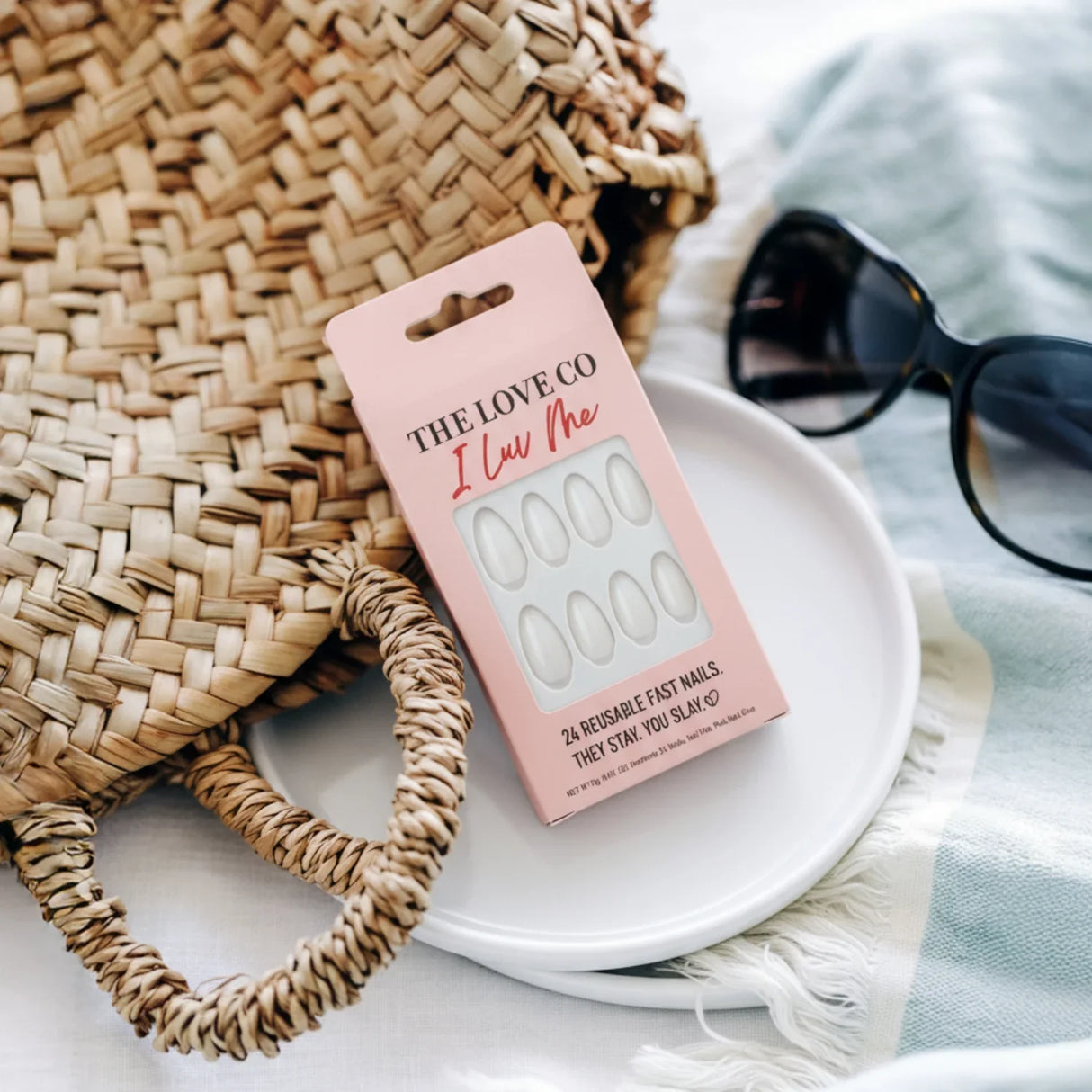 The Love Co I Luv Me press on nails in pink box with woven straw bag and sunglasses