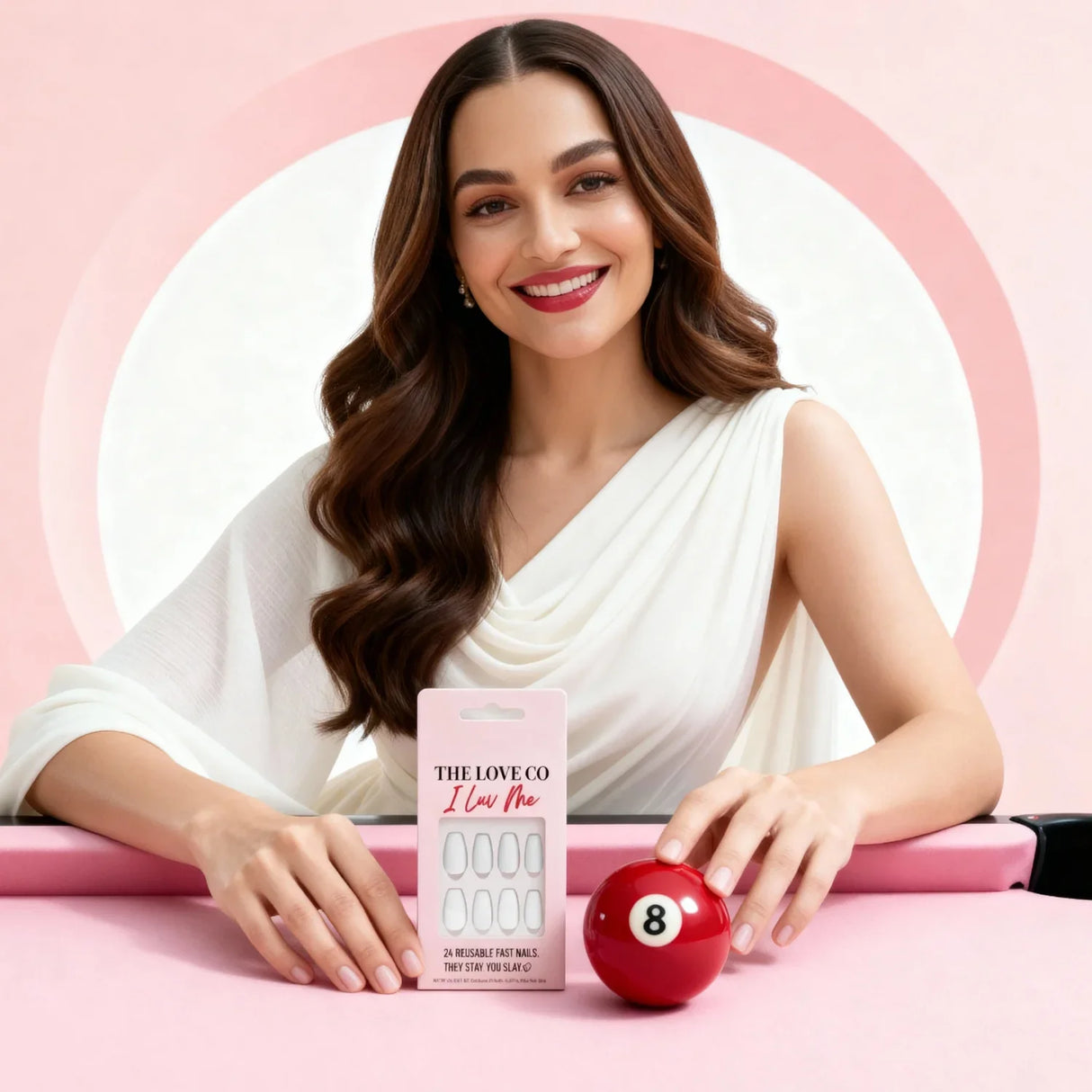 Woman in white dress with The Love Co I Luv Me reusable nails and red 8 ball on pink table
