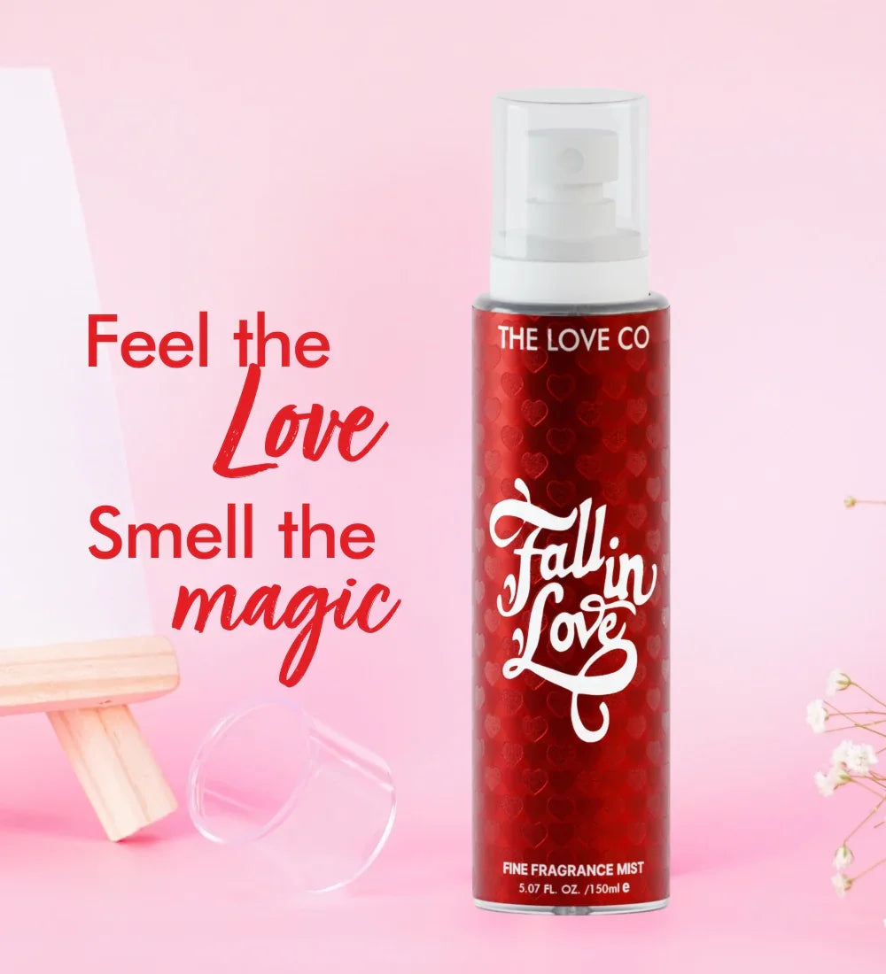 The Love Co Fall in Love body mist spray bottle on pink background with flowers and cap.