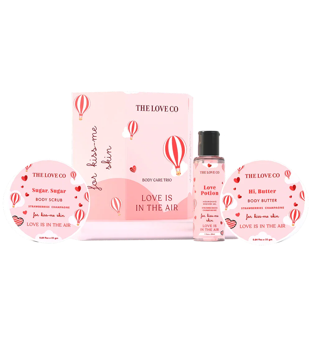THE LOVE CO Love Is In The Air body care trio with body scrub, shower gel, and body butter in pink packaging featuring heart and hot air balloon graphics.
