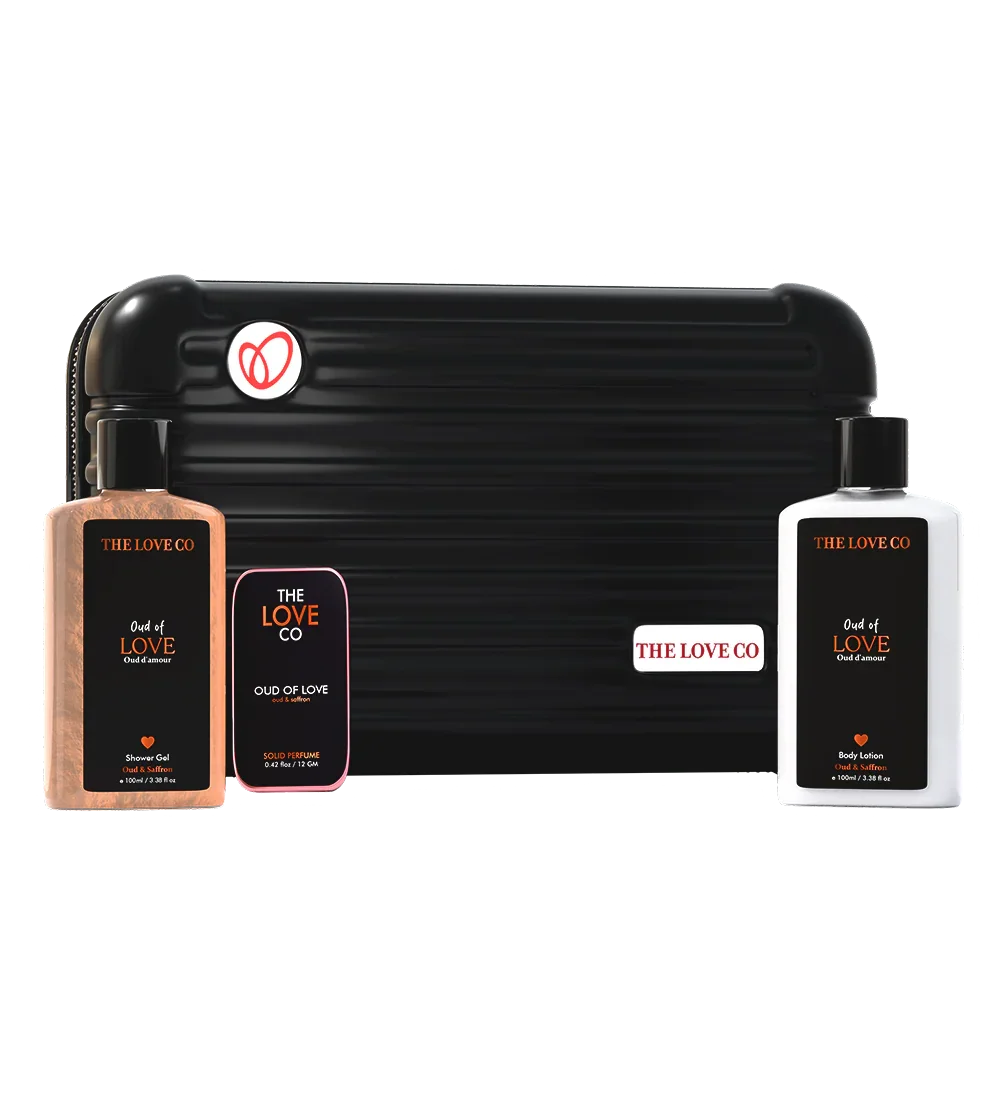 THE LOVE CO Oud of Love zipper kit with shower gel, body lotion, and solid perfume in front of a black travel case