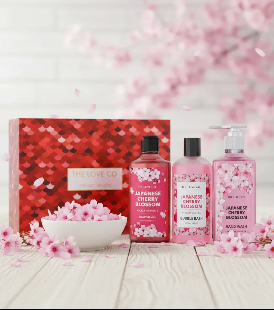 The Love Co Japanese Cherry Blossom gift box with shower gel, bubble bath, and hand wash set, surrounded by pink cherry blossoms.