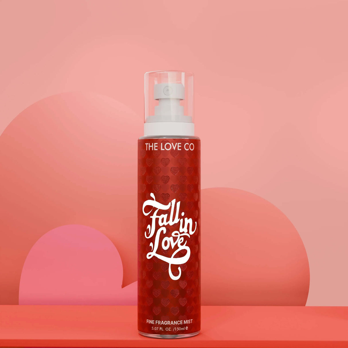 The Love Co Fall in Love fragrance mist bottle on a pink heart-themed background