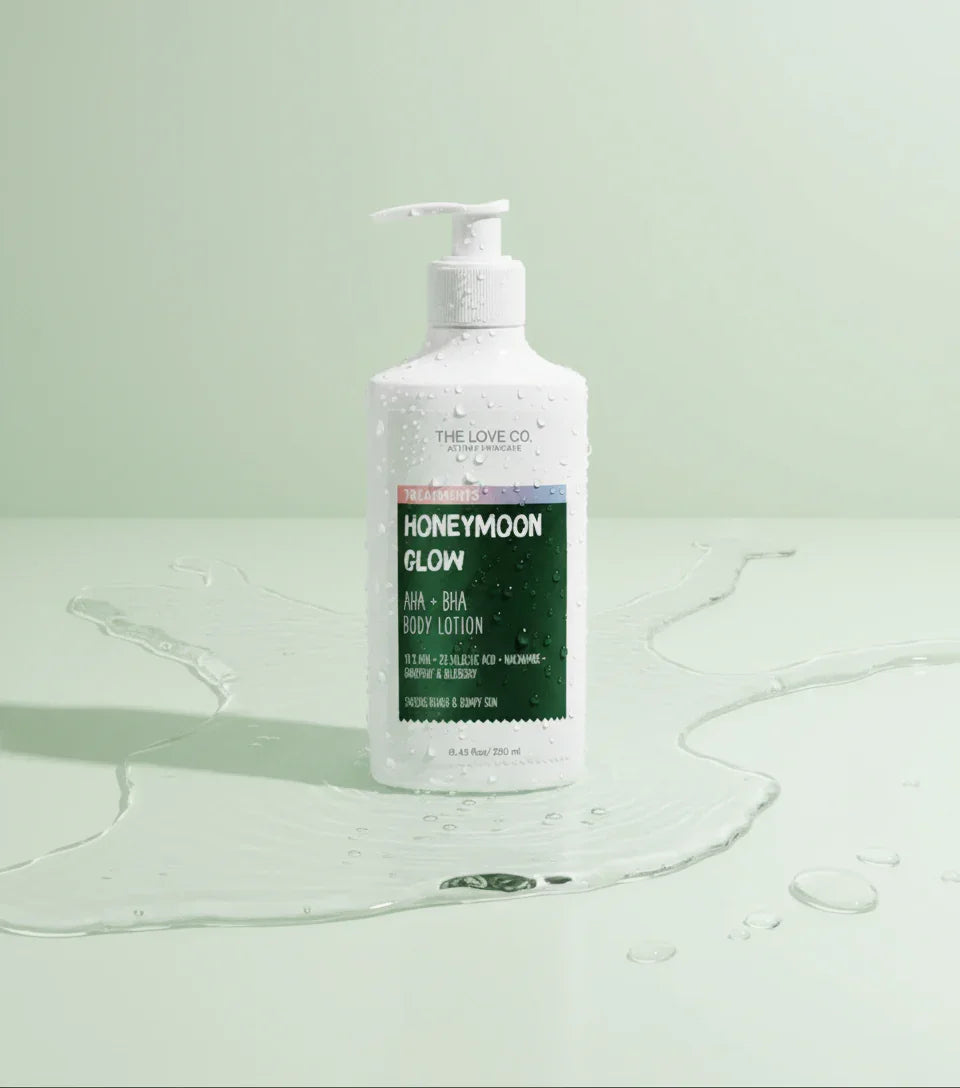 The Love Co Honeymoon Glow body lotion bottle with water drops on a light green background