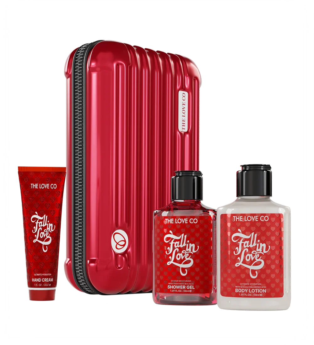Red suitcase with 'The Love Co' products including a tube, bottles of shower gel and body lotion on a white background.