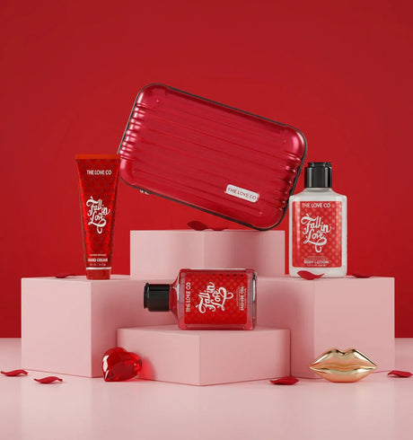 The Love Co Fall In Love gift box with hand cream, body lotion, shower gel, and red case on pink blocks