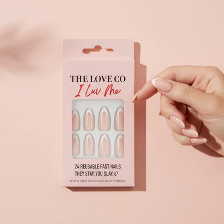 Hand with nude press-on nails holding The Love Co I Luv Me reusable fast nails box