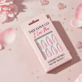 The Love Co I Luv Me pink reusable press-on nails in a pink box, surrounded by petals and glitter hearts.