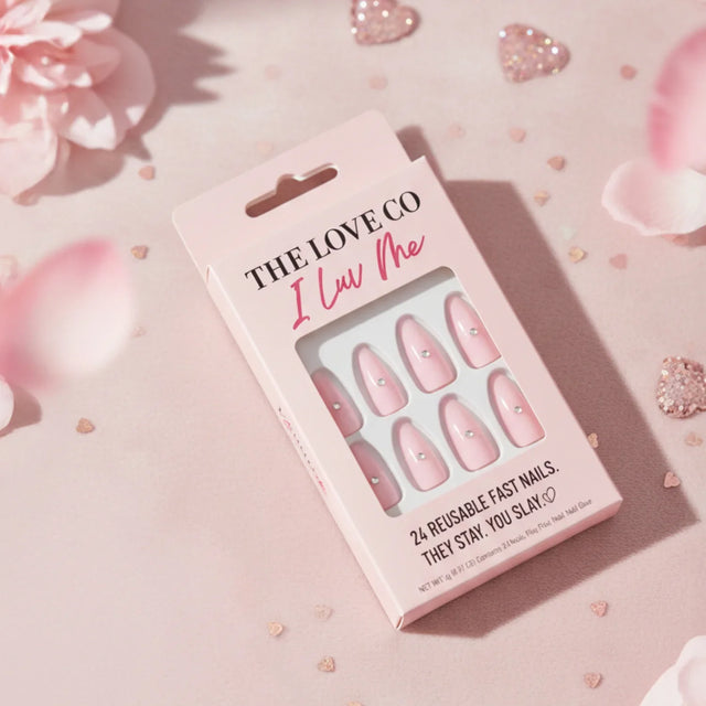The Love Co I Luv Me pink reusable press-on nails in a pink box, surrounded by petals and glitter hearts.