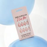 The Love Co pink press on nails set in packaging, pastel blue and white balloon background