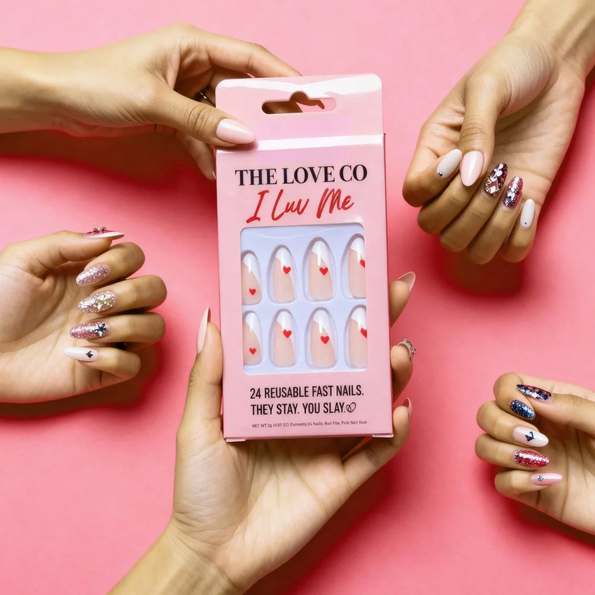 The Love Co I Luv Me press on nails pack held by manicured hands on a pink background