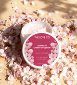 The Love Co Japanese Cherry Blossom body yogurt moisturizer surrounded by cherry blossoms