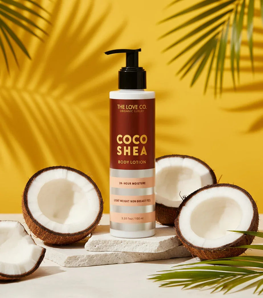 Coco Shea body lotion from The Love Co. with coconuts and palm leaves on a yellow background