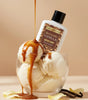 Body lotion bottle labeled 'The Love Co Romantic Vanilla' with ice cream and caramel sauce on a beige background