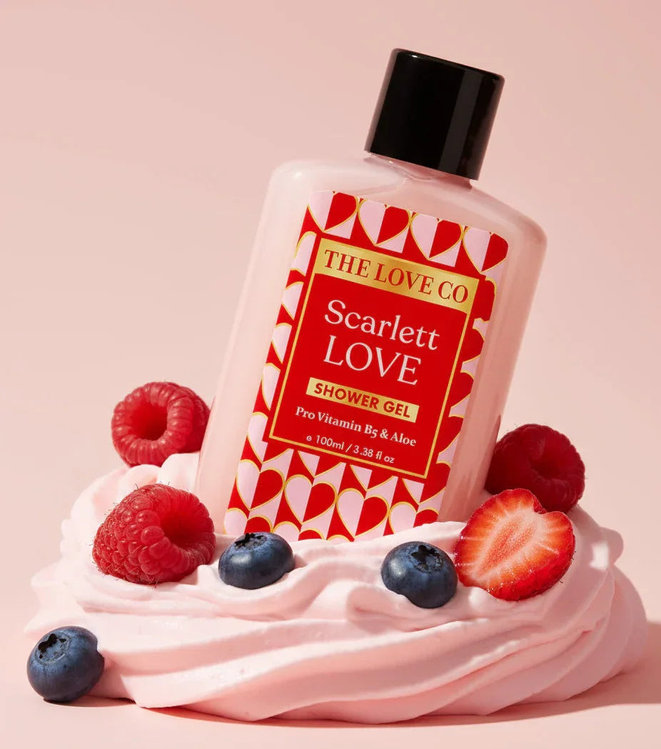Bottle of 'Scarlett LOVE' shower gel from 'The Love Co' with berries on a pink background