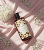 Shades of Love body wash bottle on pink satin with white flowers, elegant skincare product display