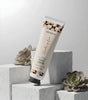 Shades of Love hand cream tube on concrete blocks with succulents, minimalist setting
