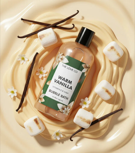Warm vanilla bubble bath bottle with vanilla beans, marshmallows, and flowers on creamy background