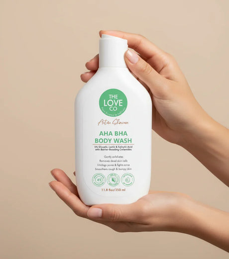 The Love Co AHA BHA Body Wash bottle held in hands on beige background