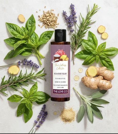 The Love Co hair oil bottle with herbs like basil, ginger, lavender, and rosemary on a light background