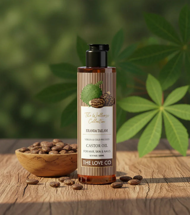 The Love Co castor oil bottle with castor beans on wooden surface and green leaves background