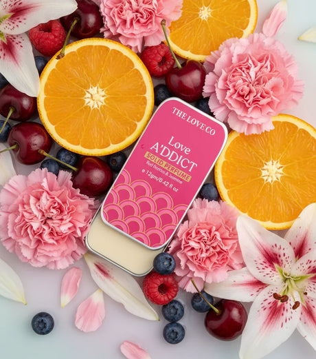 The Love Co Love Addict solid perfume tin with citrus, berries, and pink flowers
