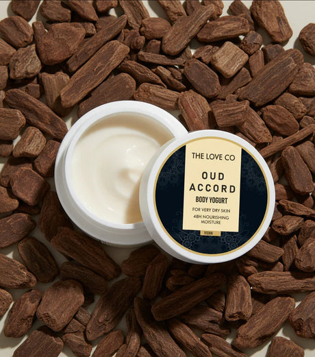 The Love Co Oud Accord body yogurt jar on oud wood pieces, moisturizing skincare product