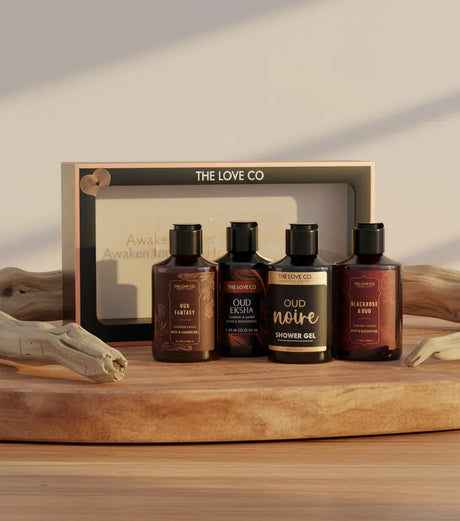 The Love Co Oud gift box with four luxury shower gel bottles on a wooden tray