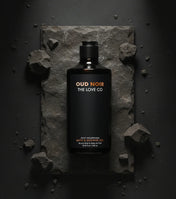 Oud Noir The Love Co body wash bottle on dark stone with rugged rocks, minimalist style