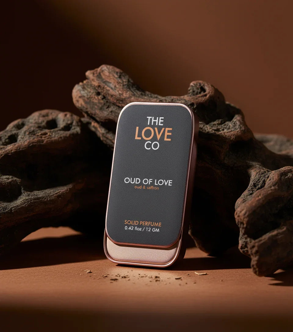 The Love Co Oud of Love solid perfume tin on brown wood with earthy background