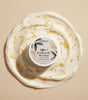 The Love Co Saffron and Kumkumadi Oil body cream with yellow petals on creamy swirl