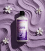 The Love Co Twilight Love body lotion bottle on textured purple background with white flowers