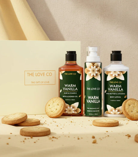 The Love Co Warm Vanilla gift box with bath and body products and cookies on a beige cloth.